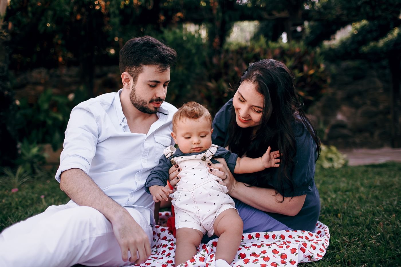 Two parents with their baby enjoying a picnic in the park